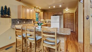 A kitchen with wooden cabinets, granite countertops, and a central island with chairs.