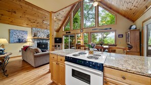 A spacious kitchen with a large island, wooden cabinetry, and a stone fireplace.