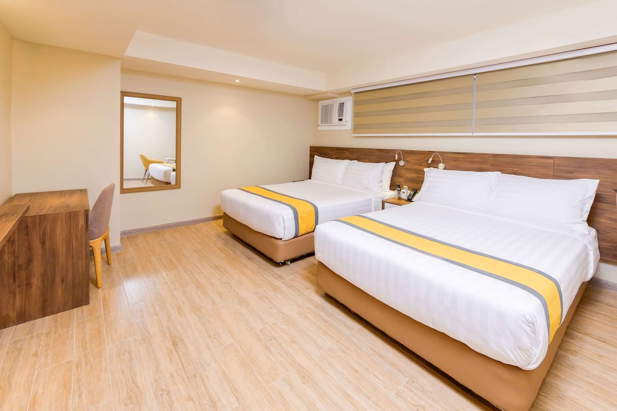 Ein Hotelzimmer mit zwei Betten, einem Schreibtisch und einem Spiegel.