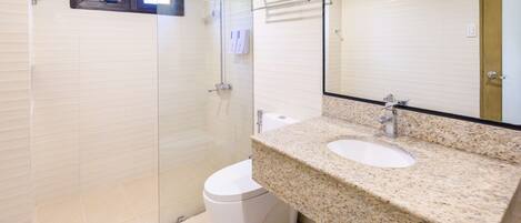 A bathroom with a glass shower enclosure, a toilet, and a granite countertop sink.