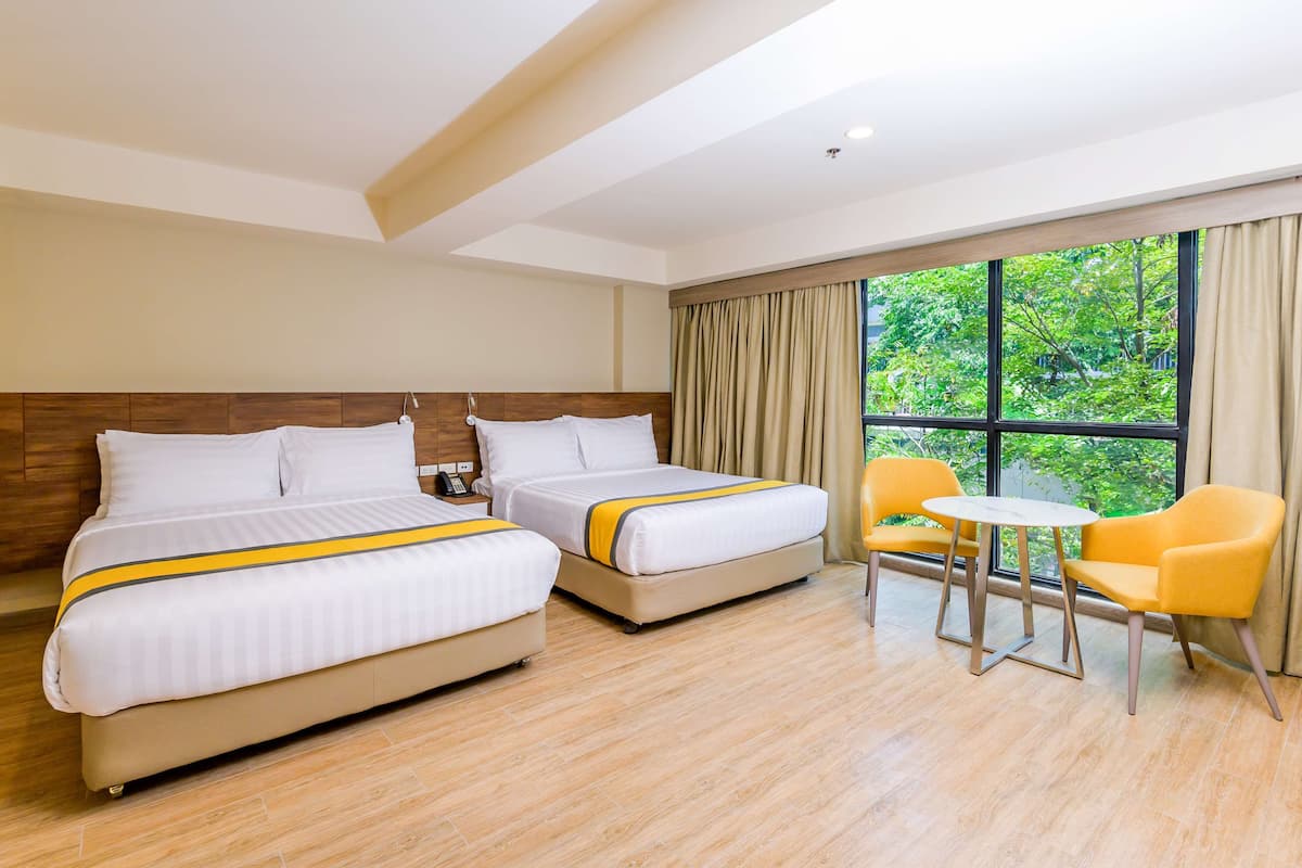 Ein Hotelzimmer mit zwei Betten, einem kleinen Tisch und gelben Stühlen.