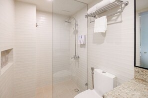 Ein modernes Badezimmer mit einer gläsernen Duschkabine, einer weißen Toilette und einer Marmorarbeitsplatte.