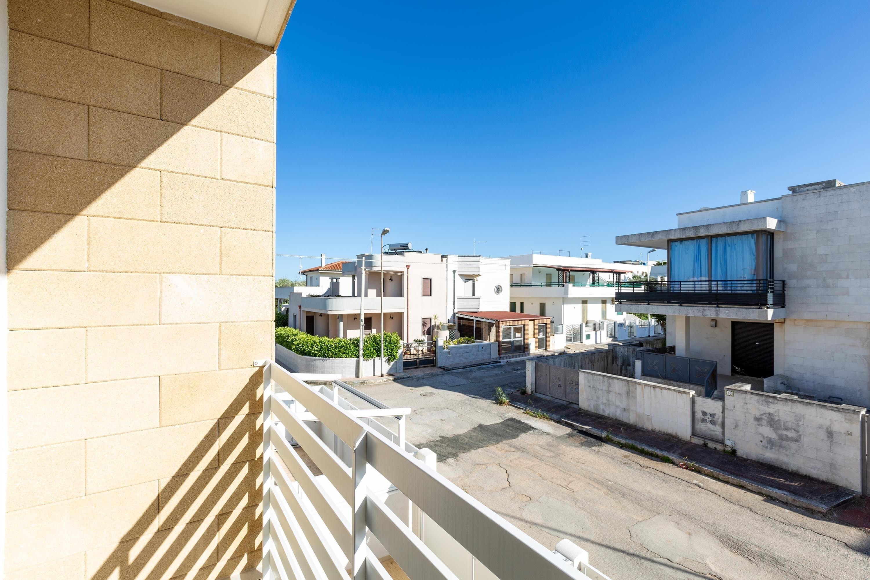 Een woongebied met een heldere lucht, met moderne gebouwen met balkons, een geplaveid binnenterrein en een witte balustrade.