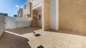 A modern building with a beige brick exterior, a flat roof, and a white door. - 3399 Bina House by Barbarhouse (Carovigno)