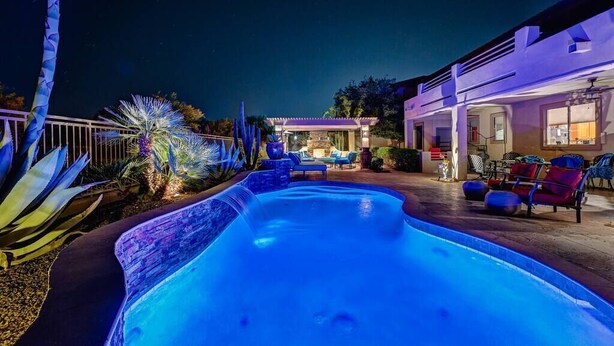 Une piscine au design moderne, entourée de mobilier d’extérieur et d’un patio bien éclairé.