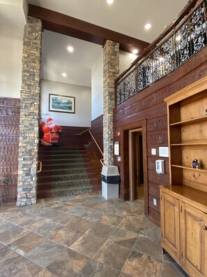 Un hall d’entrée avec un pilier en pierre, un escalier en bois et un comptoir d’accueil en bois.