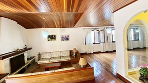 Amplia sala de estar con techo de madera, un conjunto de sofás, una chimenea y un espejo grande.