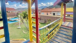 Una estructura de juegos colorida con un tobogán y una red de cuerdas.
