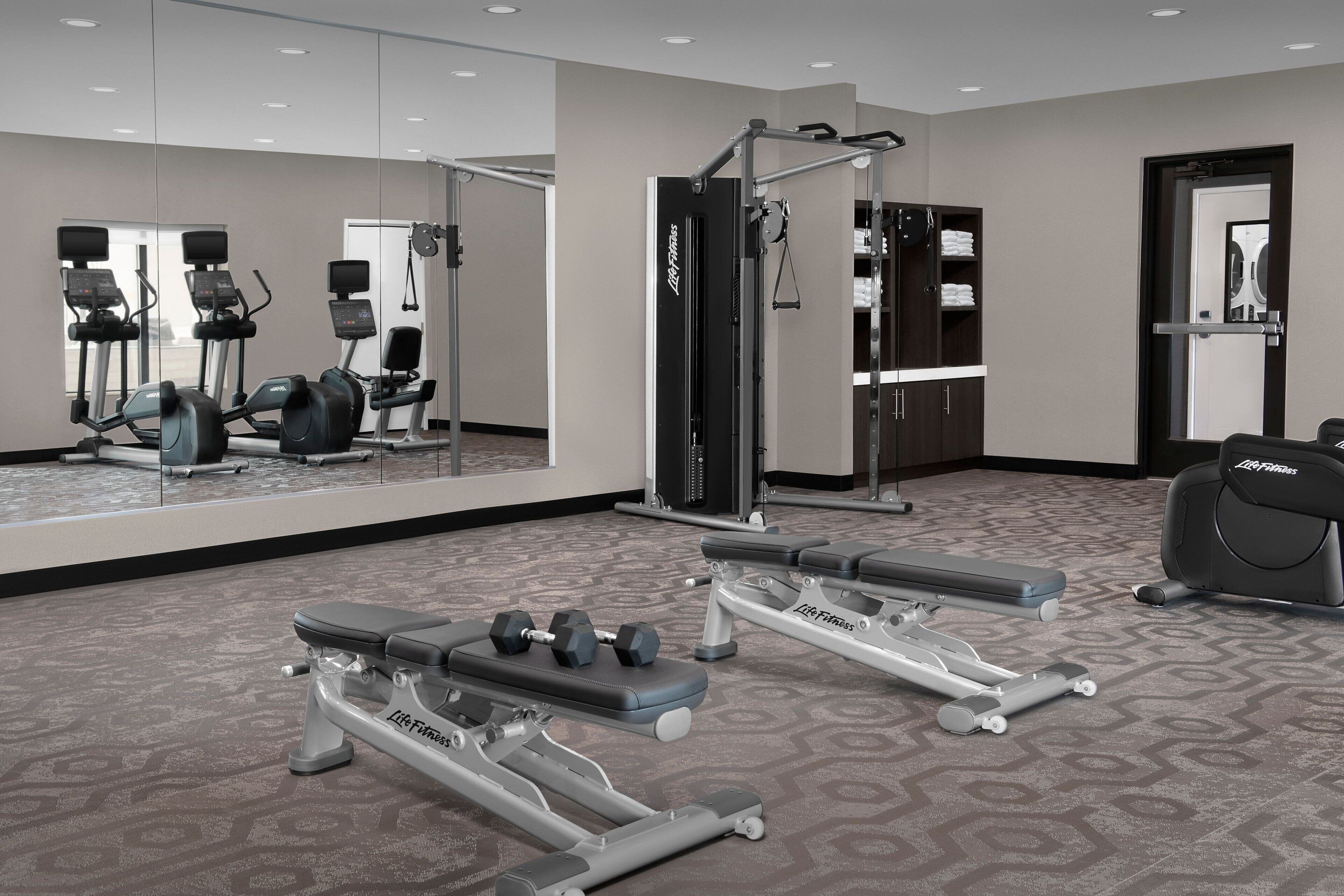 A gym with cardio machines, weight benches, and free weights.