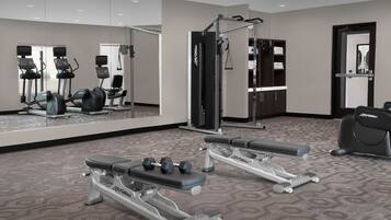 A gym with cardio machines, weight benches, and free weights.