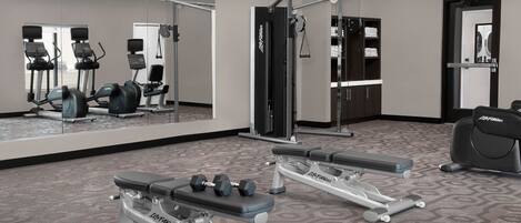 A gym with cardio machines, weight benches, and free weights.