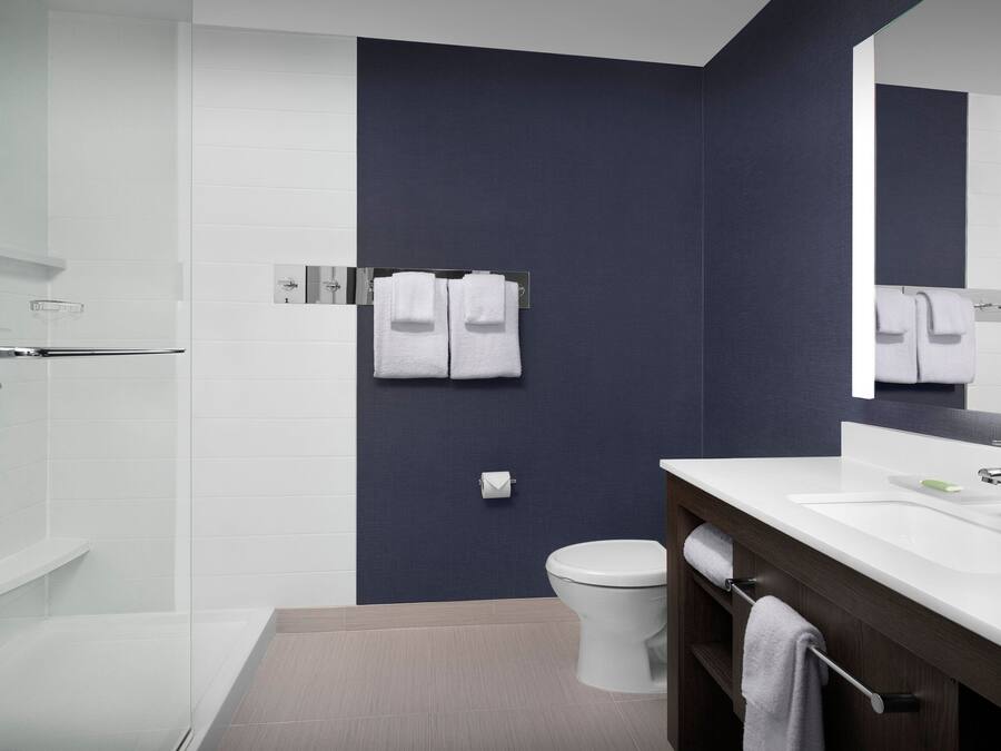 A modern bathroom with a white sink, dark wall, and a large mirror.