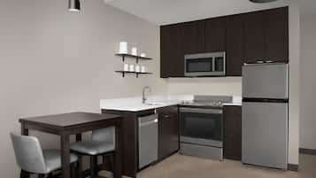 A modern kitchen with dark wooden cabinets, stainless steel appliances, a white countertop, and a bar stool.