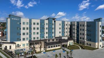 A multi-story hotel with a modern design, featuring a central courtyard with a pool and outdoor seating.