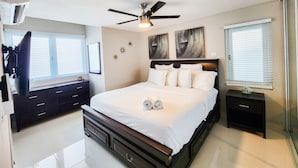 A bedroom with a bed, a ceiling fan, a nightstand, a dresser, and artwork on the wall. - 6 guests, 4 min Walk to Private Beach, casino, bowling alley and much more ! 
 (Dorado)