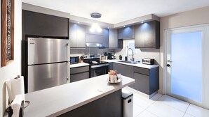 A modern kitchen with stainless steel appliances, a central island, and dark cabinetry. - 6 guests, 4 min Walk to Private Beach, casino, bowling alley and much more ! 
 (Dorado)