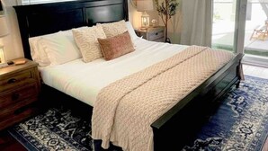 Een slaapkamer met een groot bed, een nachtkastje, een lamp en uitzicht op de omgeving.