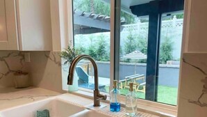 Een keuken met een dubbele spoelbak, een raam met uitzicht op een achtertuin en muren met een marmerlook.