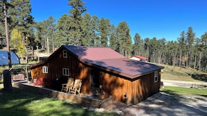 Eine rustikale Holzhütte mit Metalldach, einer Holzterrasse und zwei Schaukelstühlen.