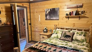 Ein gemütlicher Holzraum mit einem Bett, einer Kommode und einem Bild an der Wand.