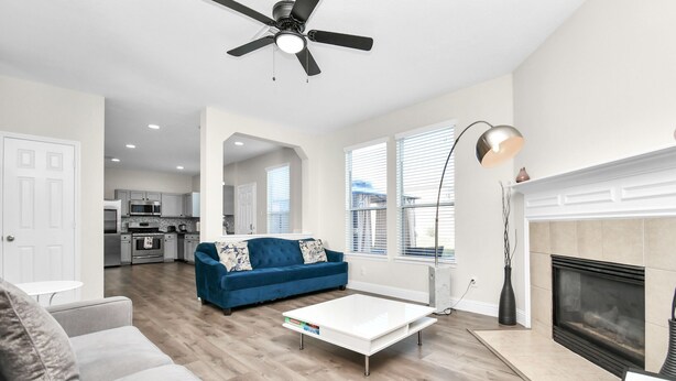 A modern living room with a blue sofa, a white coffee table, and a fireplace. - Amazing 4-BR Oasis With Pool & Backyard Bliss (Cypress)