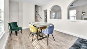 A dining area with a table and chairs, a staircase, and a view of the kitchen. - Amazing 4-BR Oasis With Pool & Backyard Bliss (Cypress)