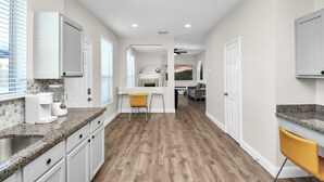 A modern kitchen with white cabinets, a granite countertop, and a wooden floor. - Amazing 4-BR Oasis With Pool & Backyard Bliss (Cypress)