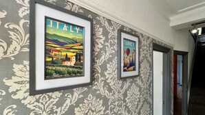 Un couloir avec un papier peint à motifs et deux tableaux encadrés accrochés au mur.