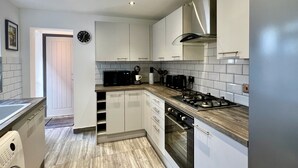 Une cuisine moderne avec des meubles blancs, une cuisinière, un four et un four à micro-ondes.