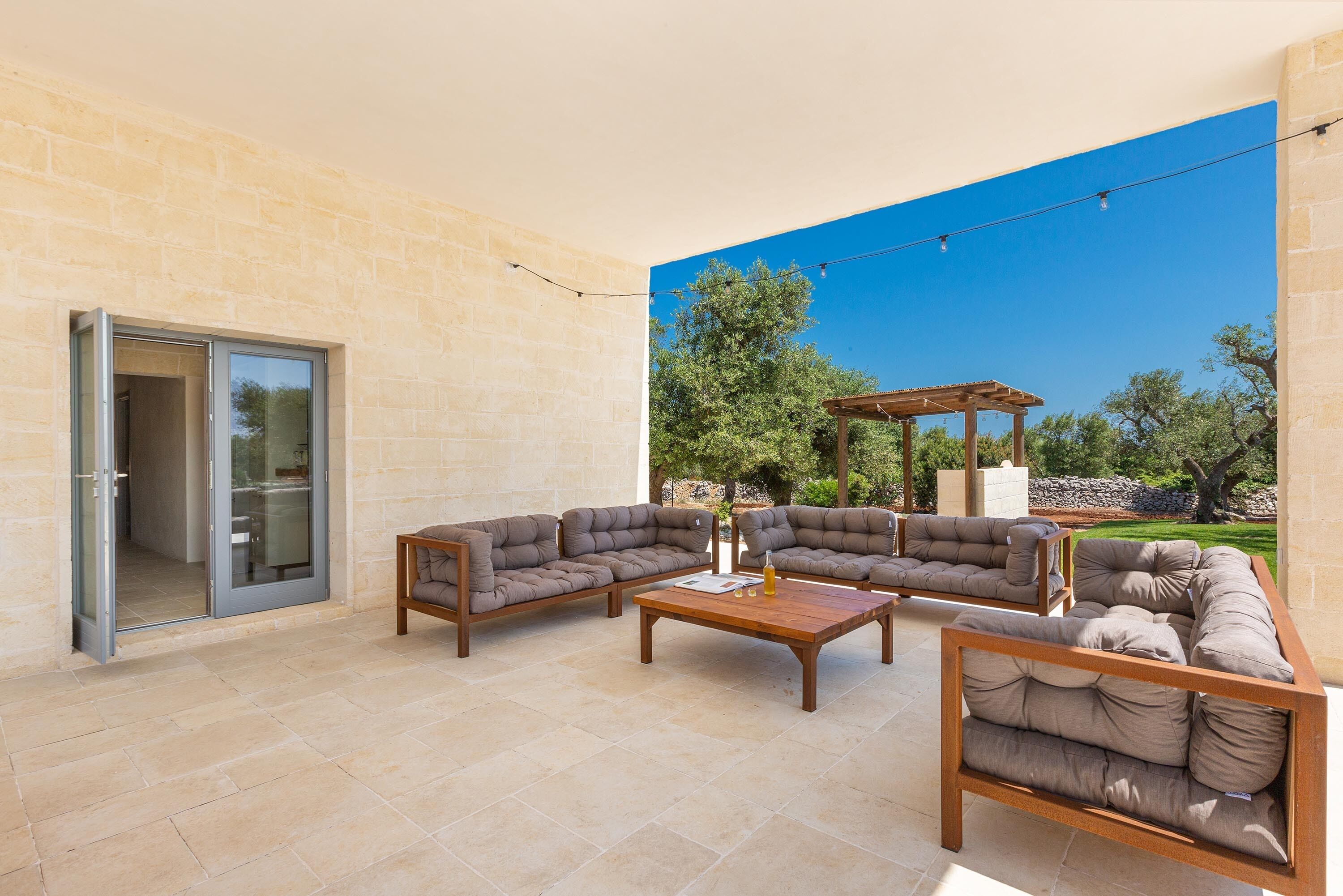 Un patio al aire libre con un conjunto de sofá, una mesa de centro y una pérgola.