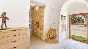 A room with a wooden dresser, a stone wall, and a large wooden door leading outside.