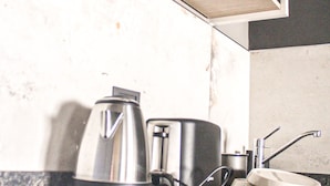 A modern kitchen with a built-in coffee maker, a kettle, and a sink. - Suites Isla Verde (La Rioja)