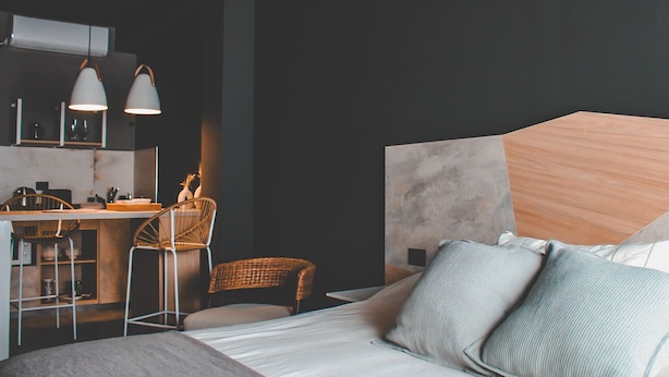 A modern hotel room with a large bed, a desk with a chair, and a small seating area. - Suites Isla Verde (La Rioja)