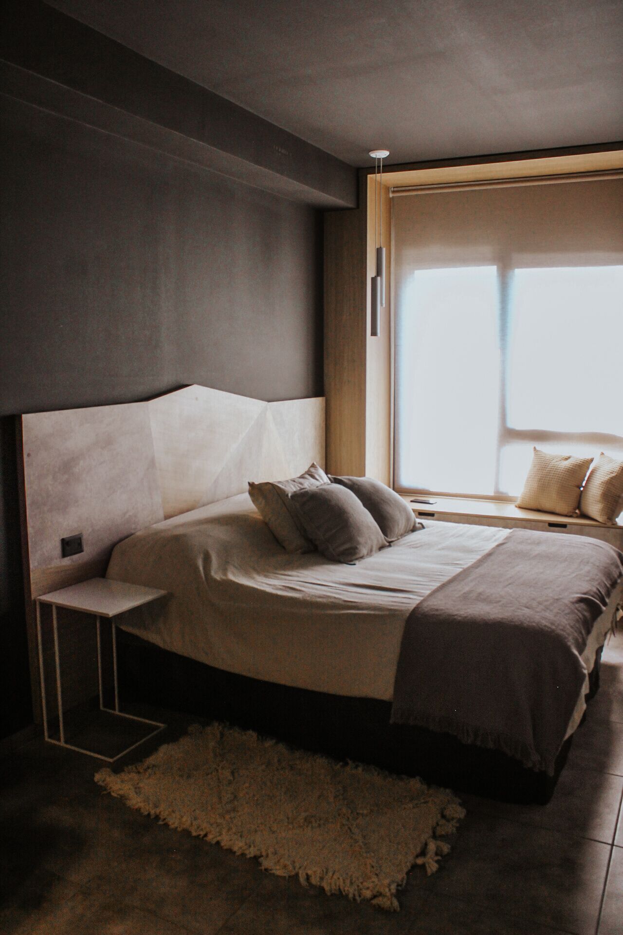 Un dormitorio moderno con una cama grande, una mesita de noche y una ventana con cortinas.