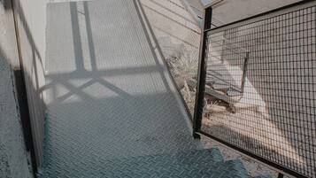 A staircase with metal railings and a metal fence, leading to a covered area with numbered lockers.