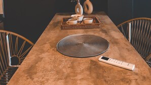 A dining table with a modern pendant light, two vases, and a tray with cups and a remote control. - Suites Isla Verde (La Rioja)