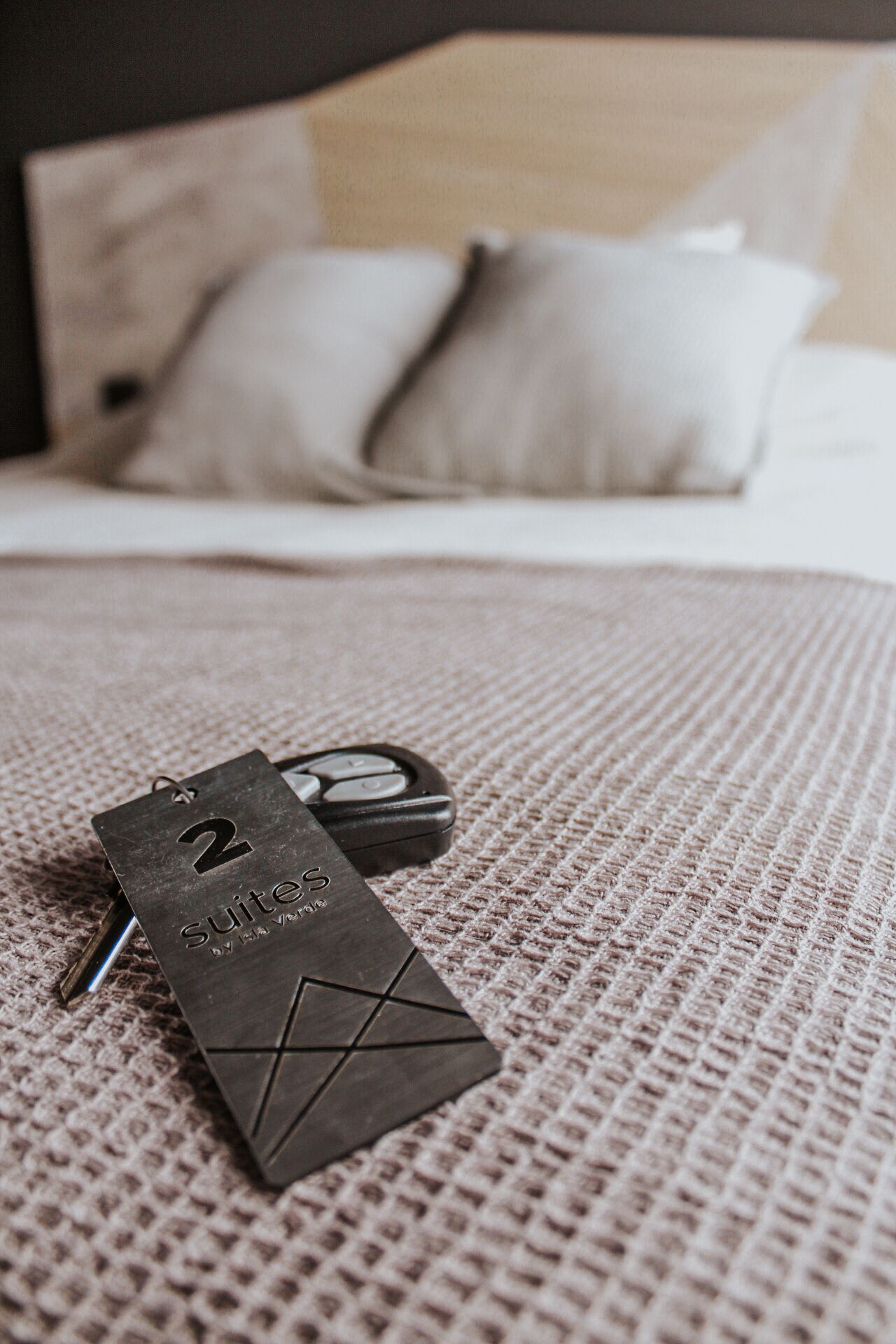 Une chambre d’hôtel avec un lit, une couverture à motifs et un porte-clés indiquant « Suite 2, HVA Verace ».