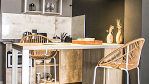 A modern kitchen with a marble countertop, two pendant lights, and a bar area with two stools. - Suites Isla Verde (La Rioja)