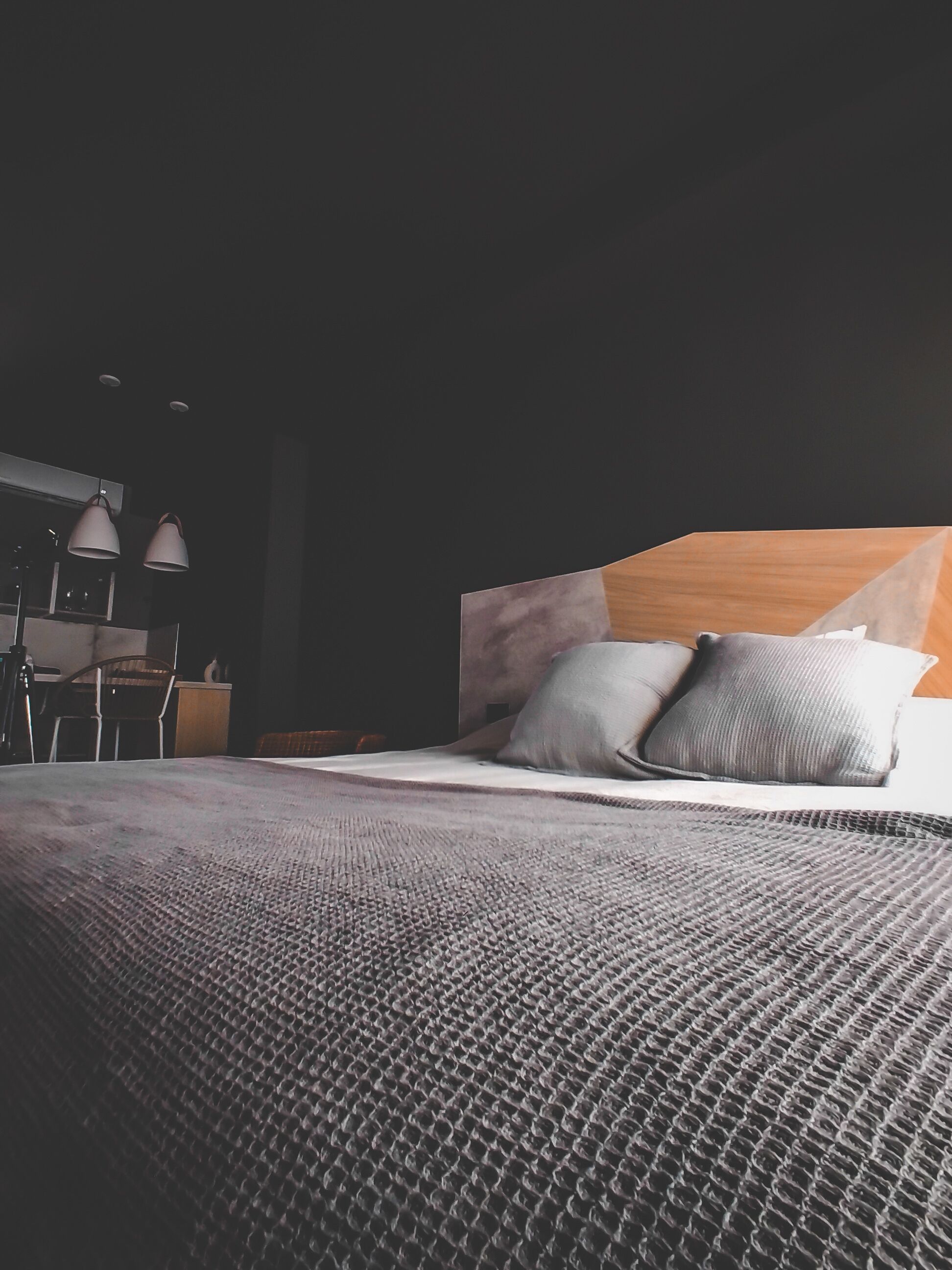 A modern bedroom with a large bed, a wooden headboard, and a small desk with a chair.