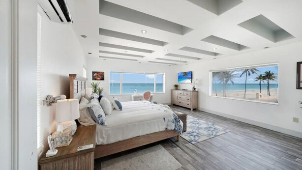 A bedroom with a large bed, a view of the beach, and a ceiling with recessed lighting. - *Magical Beachfront King Escape*

 (Hollywood)