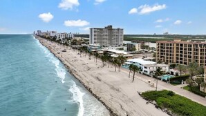 A coastal cityscape with a beachfront, high-rise buildings, and a clear sky. - *Magical Beachfront King Escape*

 (Hollywood)