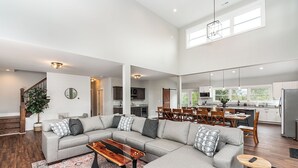 A spacious living room with a sectional sofa, a coffee table, and a dining area with a table and chairs. - New! Farmhouse Epic Covered Porch FirePit (Faber)