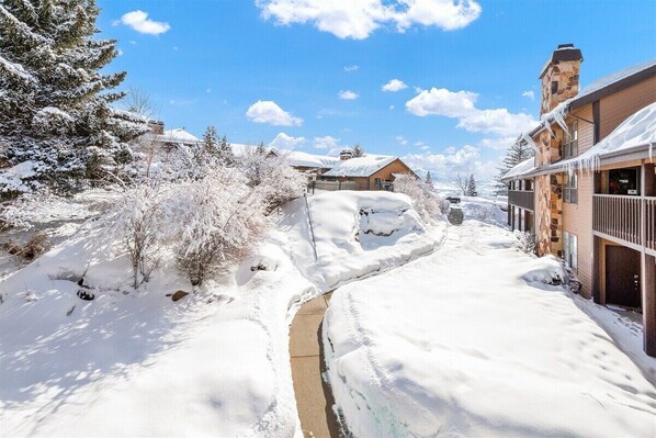 Schneebedeckte Landschaft mit Gebäuden, einem Weg und einem kleinen Bach.