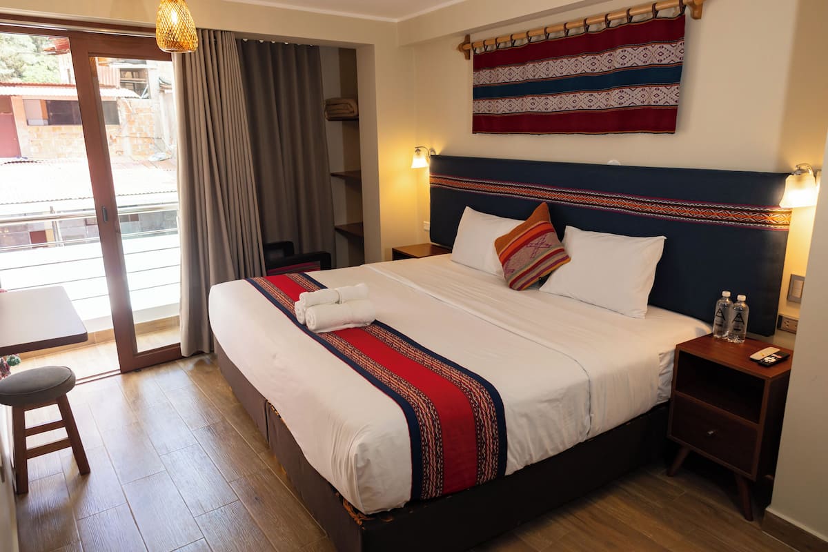 Una habitación de hotel con cama, mesitas de noche, escritorio y una silla.
