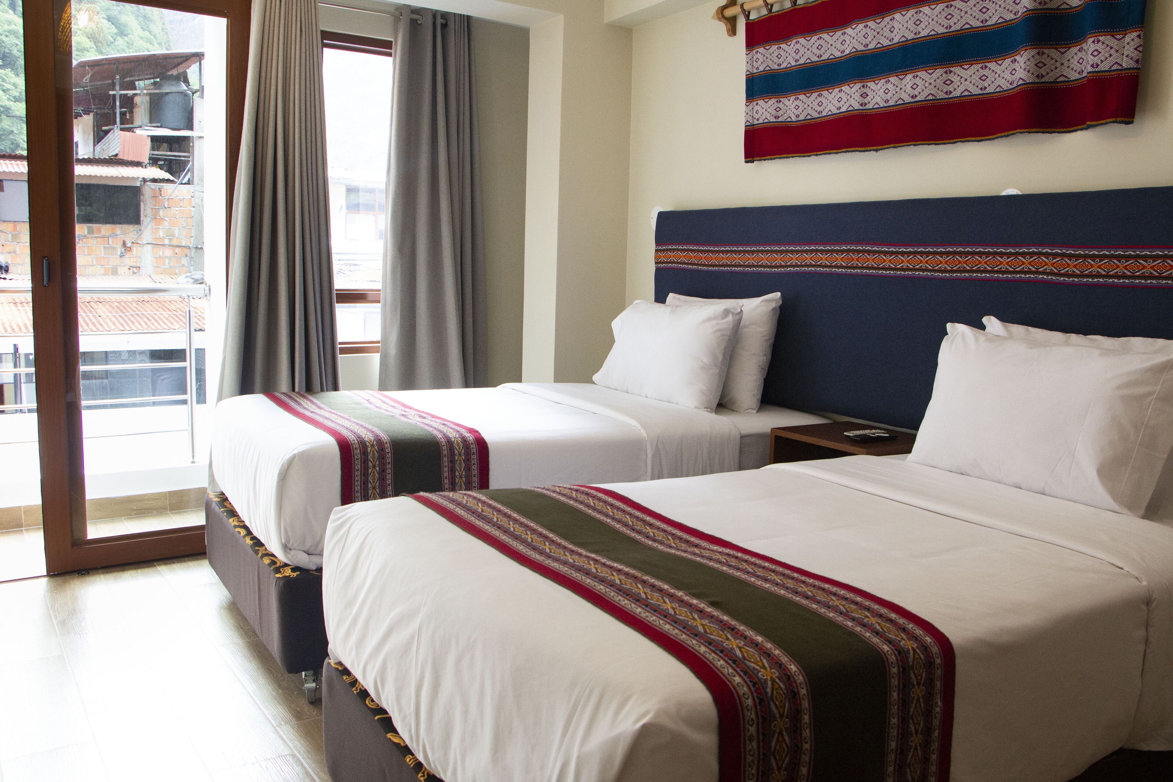Habitación de hotel con dos camas, un balcón y vistas al exterior.