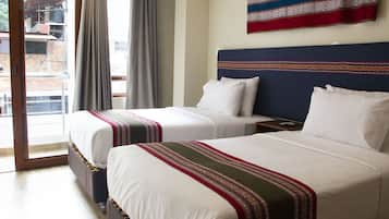 A hotel room with two beds, a balcony, and a view of the outside.