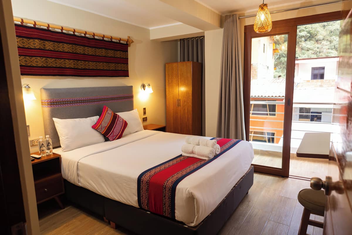 Habitación de hotel con cama, mesita de noche, armario y vistas al exterior.