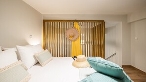 A bedroom with a bed, pillows, a hat, and a striped partition. - Corfu Luxury Loft by Corfuescapes (Corfu)