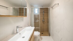 A modern bathroom with a large mirror, a white sink, a glass-enclosed shower, and a wooden vanity. - Corfu Luxury Loft by Corfuescapes (Corfu)