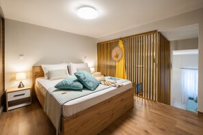 Een moderne slaapkamer met een houten bed, een nachtkastje, een wandlamp en een decoratief wandpaneel.